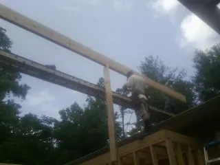 Carpenter setting a ridge beam over a new addition frame — Ice Dam Removal by Roofing Brothers in Deansboro