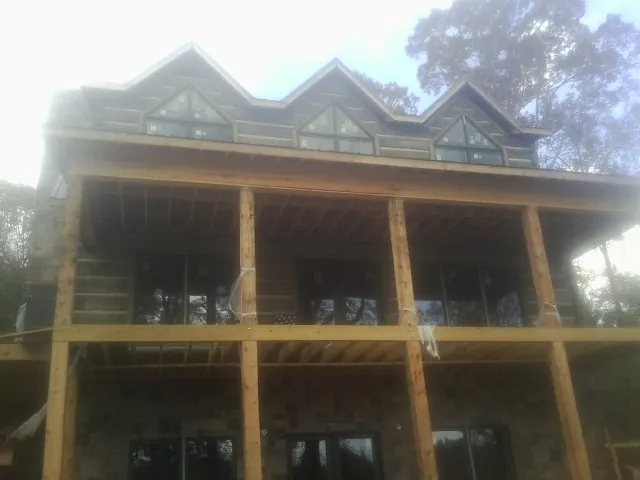 Dormers and porch framing on a large log home under construction — Roof Coating work by our crew in Deansboro