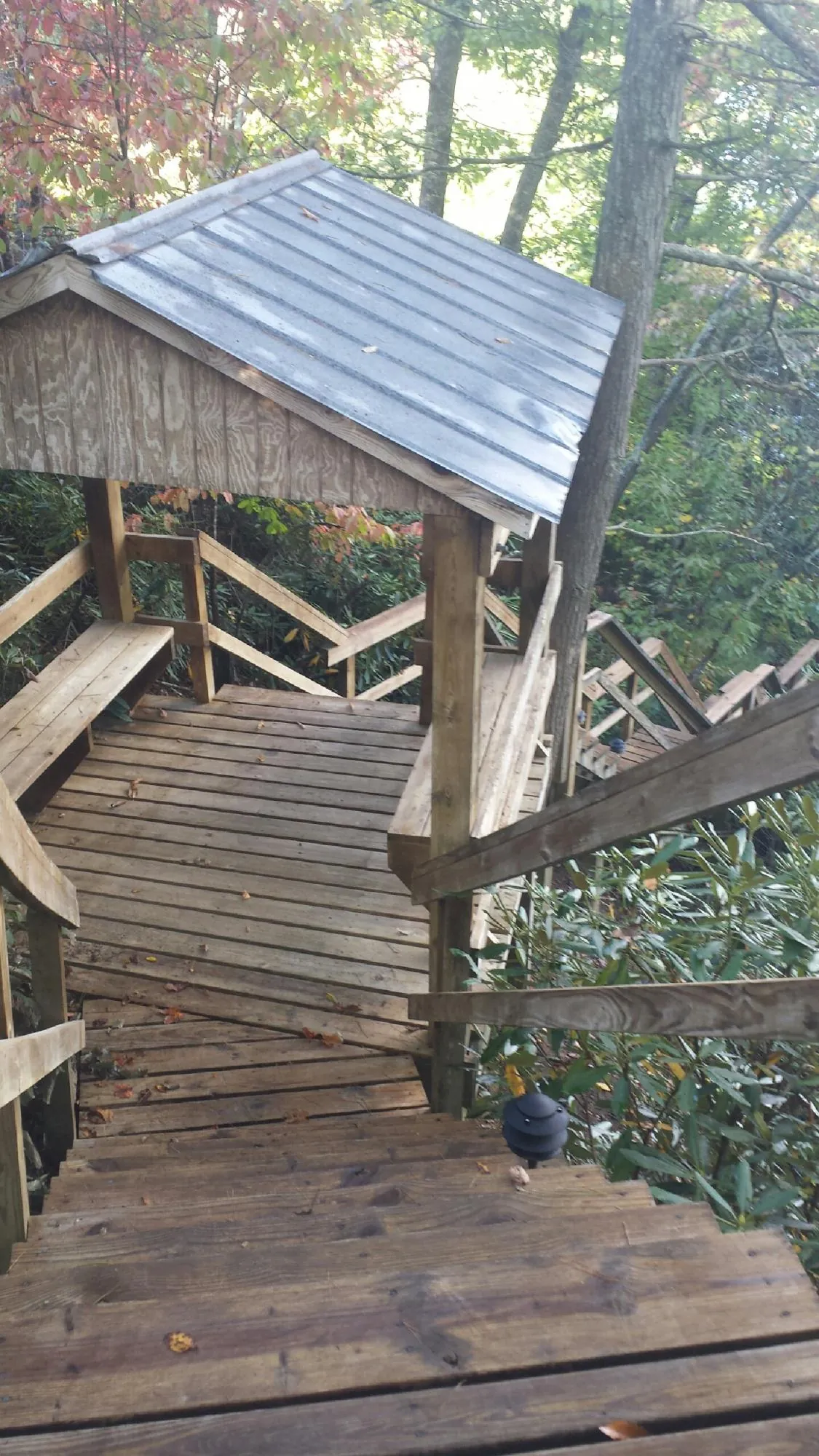 Metal roofed shelter over wooden steps on a wooded walkway — Skylight Repair & Installation work by our crew in Deansboro