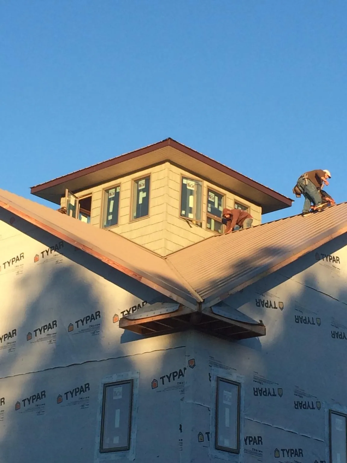 Roofers working around a rooftop cupola on a new metal roof at sunset — Roof Waterproofing in Deansboro by Roofing Brothers
